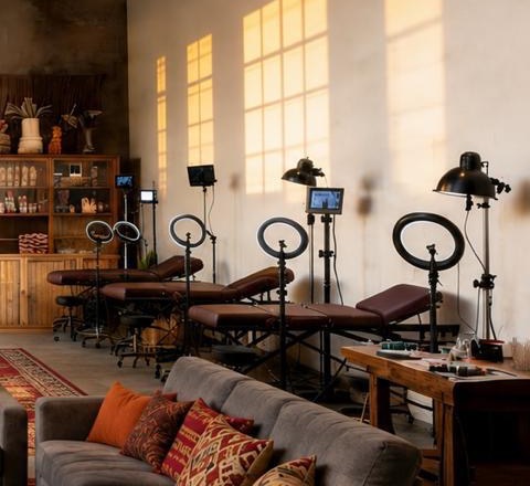 Tattoo stations with ring lights against a sunlit concrete wall at Club Bagarre